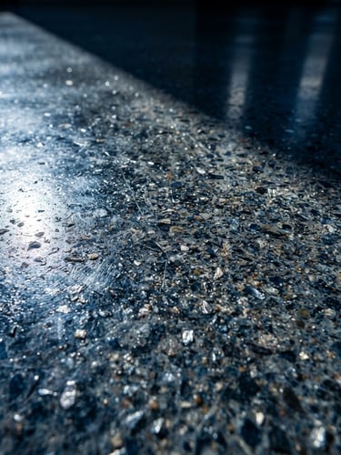 Macro close-up of a flawless polished concrete surface with metallic reflections, sharp directional light highlighting the fine aggregate texture, high contrast.