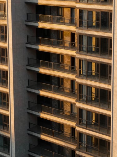 High-contrast architectural close-up of a modern luxury estate facade, golden-hour sunlight casting long dramatic shadows, 35mm