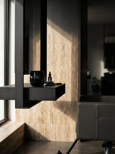 Sharp editorial photography of a minimalist premium salon interior, high-contrast side lighting, deep charcoal and warm travertine tones, macro depth of field, clean geometric lines