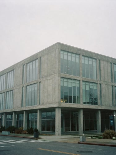 Wide-angle architectural perspective of a modern concrete and glass building in Seattle, misty morning fog, soft overcast daylight, cool desaturated tones, 35mm film.