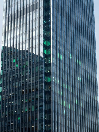 Sleek high-tech photography, wide clean architectural shot of a modern financial hub with glass facades, cool daylight with electric green reflections, deep blue shadows