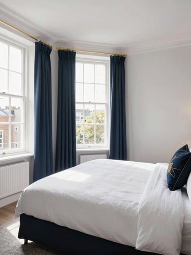 A pristine and bright London Airbnb bedroom with freshly made white linen, natural sunlight streaming through a window, deep navy and gold decorative accents, wide environmental shot