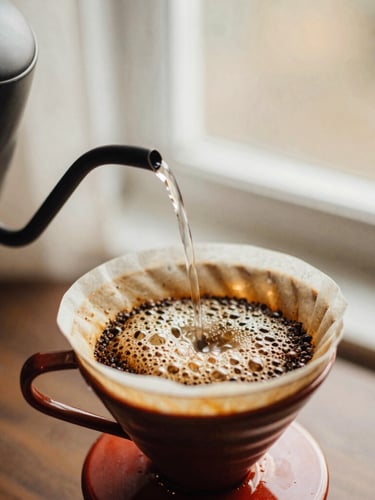 Slow-motion hot water pouring from a gooseneck kettle over coffee grounds in a ceramic dripper, showing the active bubbling bloom, warm side-lighting