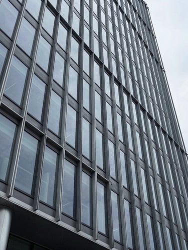 Wide architectural perspective of a modern steel and glass skyscraper facade in Wilmington, sharp geometric lines, overcast daylight, cold tones, high-end corporate permanence.