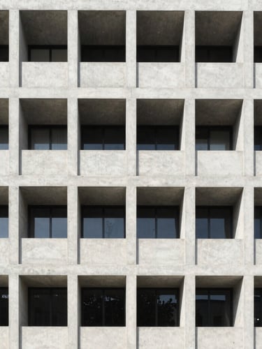 Symmetrical architectural shot of a modern concrete building facade, bright natural daylight, clean technical lines