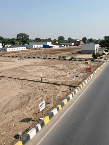 Wide-angle environmental shot of a clean, surveyed industrial plot along Delhi Road in Hisar under bright midday sun, showing clear boundary markers and access road