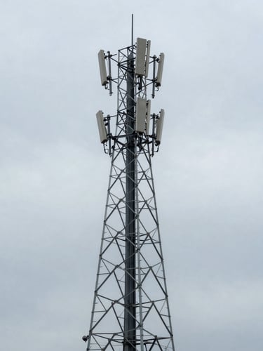 Wide environmental shot of a heavy-duty telecommunication tower against cold overcast sky, desaturated steel tones, sharp focus, 35mm lens.