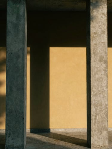 Minimalist architectural photography of concrete pillars casting long sharp shadows on a golden wall, direct sunlight, 35mm