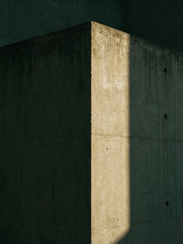 Minimalist architectural concrete corner under sharp direct sunlight, deep shadows, dark forest green tones, 35mm