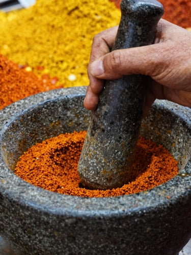 Close-up of hands grinding spices in a traditional mortar and pestle, vibrant colors, harsh market lighting, focus on texture, no text.