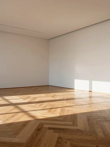 A wide architectural angle of an empty, pristine gallery room with sunlight casting long shadows across a flawless herringbone oak floor.