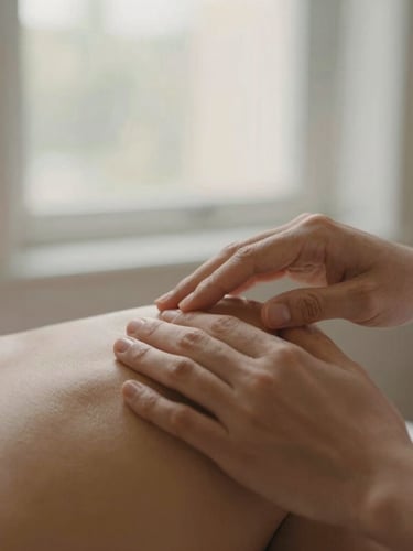Hands-on professional therapeutic touch on a shoulder, soft natural window light, warm tone, shallow depth of field, 35mm photography