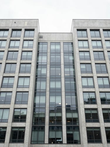 Symmetrical wide-angle architectural shot of a modern corporate headquarters facade, clean concrete and glass panels, overcast daylight, desaturated cool tones