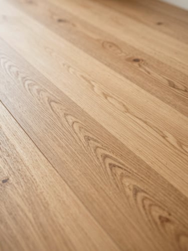 Extreme close-up of wide-plank white oak hardwood floor, shot in north-facing daylight, grain and saw marks visible, a clean seam running diagonally from corner to corner, warm honey tones