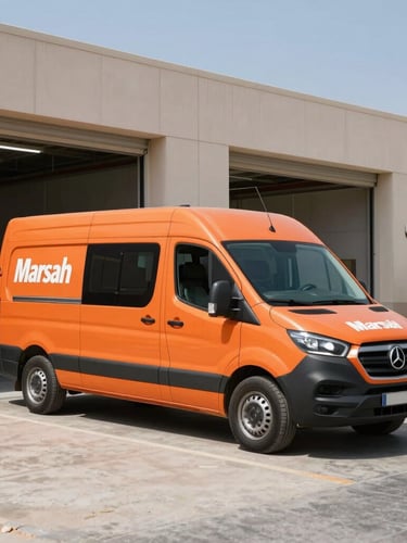 A branded safety-orange service van parked outside a clean modern workshop in Marsa Dubai, bright daylight, high-contrast industrial look.