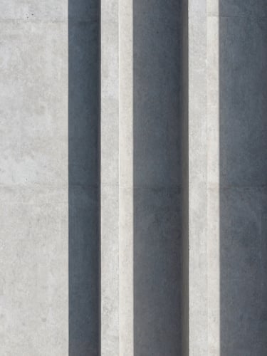 Abstract architectural shadow on a light gray concrete wall, clean vertical lines.