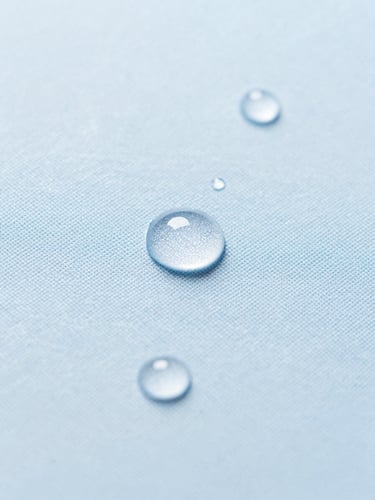 Macro photograph of water droplets perfectly beading on a clean slate blue fabric texture, bright natural daylight, 35mm lens