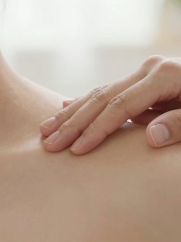 Close-up of professional hands performing targeted muscle therapy on a shoulder, soft diffused natural light, warm editorial photography, 35mm.