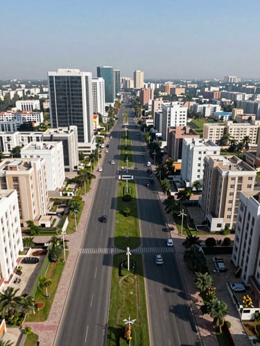 Wide symmetrical aerial drone shot of DHA Phase II Islamabad, showcasing structured paved roads, green belts, and modern residential architecture under crisp blue daylight.