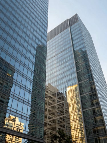 Wide-angle architectural photograph of glass skyscraper facades in Miami Brickell, sharp perspective looking up, bright daylight reflecting off windows, cool slate and deep blue tones.