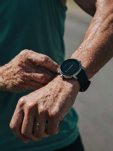 Close-up of hands adjusting a sports smartwatch on a runner's wrist, sweat drops visible, dramatic side lighting, cool athletic tones.