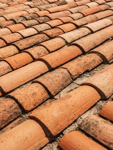 Close-up of traditional terracotta roof tiles aligned perfectly under bright Mediterranean sunlight, warm orange tones, editorial construction photography, 35mm lens