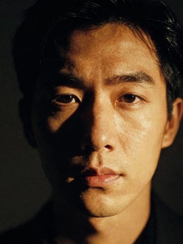 Dramatic close-up portrait of a character actor under warm spotlight, rich shadows, high-contrast chiaroscuro, cinematic 35mm film style.