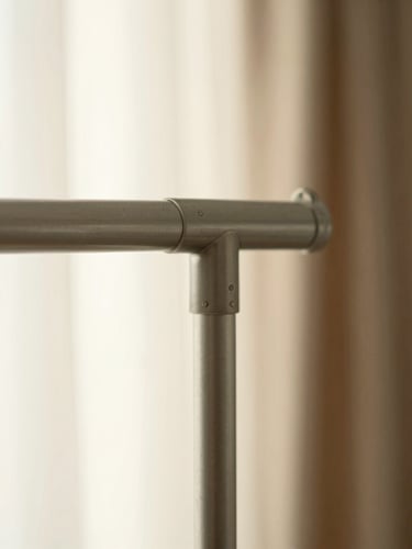 A close-up of a warm grey steel garment rack joint, highly detailed craftsmanship, soft morning light, shallow depth of field
