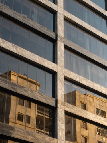 Close-up of clean architectural lines of a financial district building in Colombia, sharp geometric shadows, gold reflections on glass facades, daylight, premium corporate style.