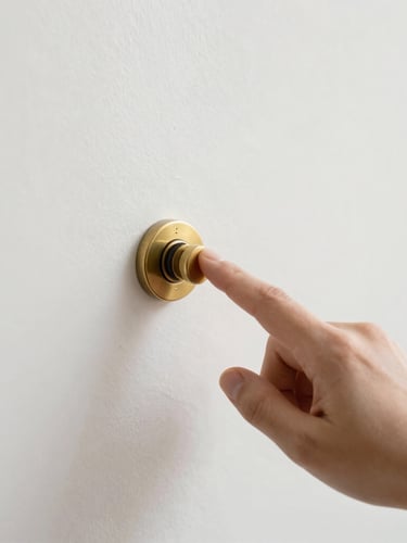 A hand reaching to flip a solid brass toggle switch on a clean, light-filled plaster wall, soft natural daylight, shallow depth of field