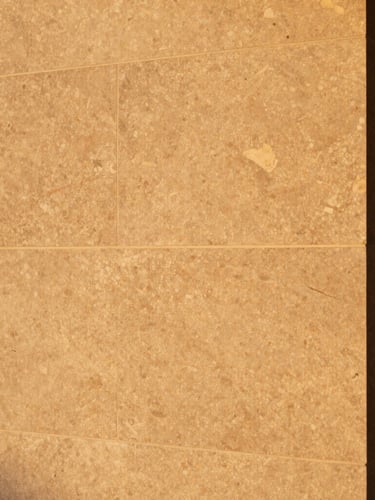 Primer plano cinematográfico de piedra natural texturizada y bronce cepillado bajo luz cálida de atardecer, atmósfera de hotel boutique de alta gama.