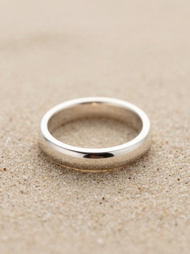 Extreme macro shot of a raw, hand-polished silver ring, architectural lines, soft diffused natural daylight, warm sand background