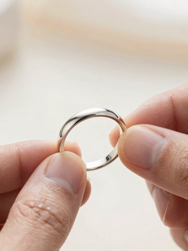 Extreme close-up of a jeweler hand-polishing a raw silver band, soft natural light, dust particles in air, macro focus