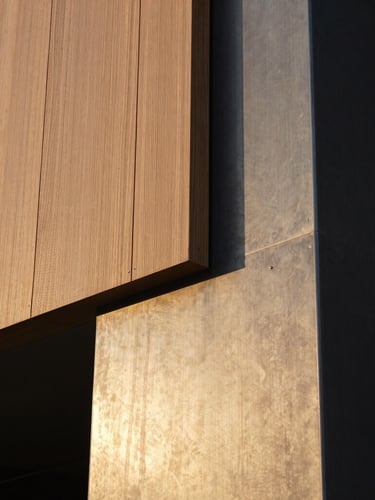 Extreme close-up of pristine material transitions, wood meeting raw steel on a modern architectural column, sharp focus, dramatic golden hour lighting