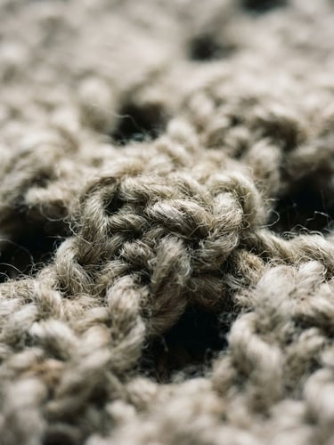 Macro detail crop of heavy-gauge raw wool weave, soft north-facing window light casting deep shadows into the crevices, muted oatmeal and bone tones, shallow depth of field, 35mm