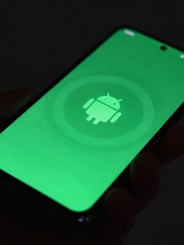 Sleek dark-mode technology photography, macro close-up of a hand holding an Android phone showing a fluid, glowing green user interface, shallow depth of field, 35mm