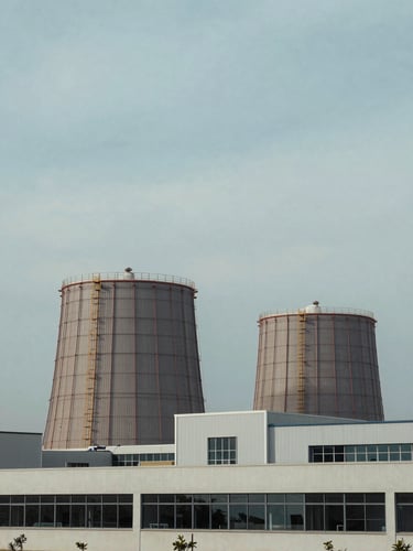 An architectural perspective of a modern industrial energy facility under a soft overcast sky, desaturated blue tones, 35mm corporate photography
