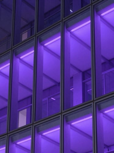 Macro shot of structured architectural glass facade reflecting cool violet neon light, clean lines, high contrast.