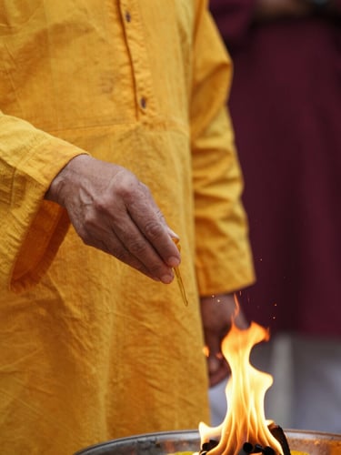 Close-up of a priest in traditional saffron attire pouring ghee into a sacred fire, warm golden glow, shallow depth of field, editorial photography