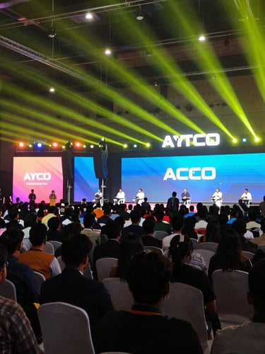 Wide environmental shot of a packed tech conference in Bangalore, bright colorful stage lighting, dynamic perspective
