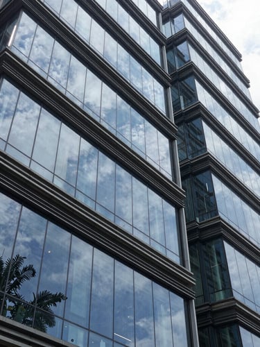 High-contrast architectural shot of a modern Indian corporate headquarters in Bengaluru, sharp glass reflections, clean lines, daylight.