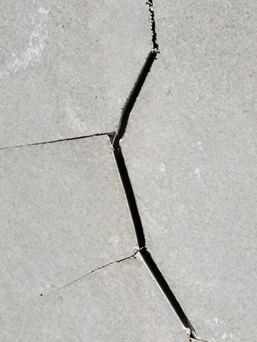 Macro shot of a severe hairline foundation crack in concrete basement wall, bright natural revealing light, no shadows, high-contrast structural details