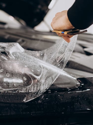 Installer applying automotive vinyl wrap with a squeegee in a dust-controlled bay