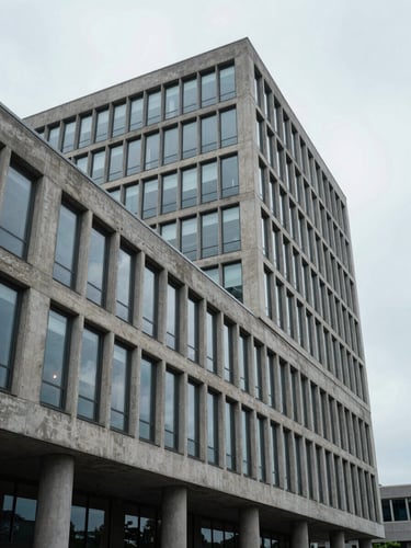 Cool, overcast daylight on brutalist corporate architecture, concrete and glass facade, clean angles, wide architectural perspective