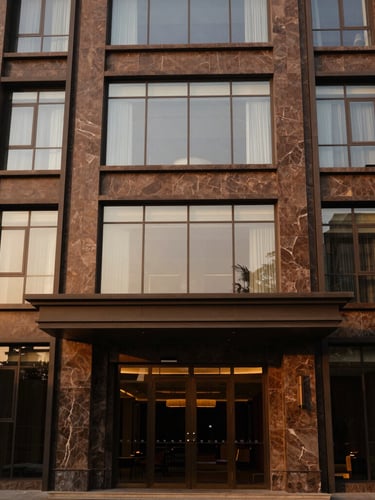 Architectural exterior of a modern premium hotel in Gulberg Lahore, warm golden-hour sunlight reflecting off clean glass and stone facade, 35mm.
