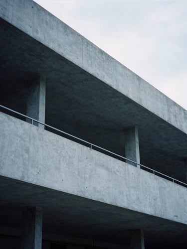 Architectural crop of a modern concrete and steel structure with clean lines, soft overcast daylight, cool desaturated blue and charcoal tones, 35mm photography