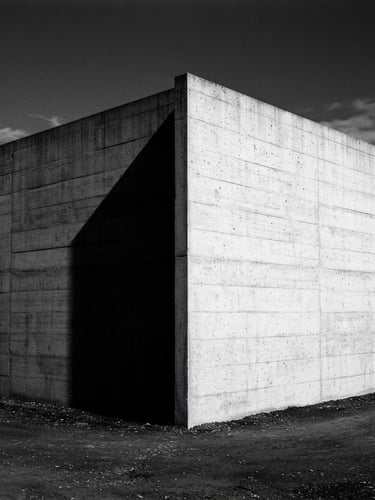Minimalist architectural photography. Stark concrete corner of a Swiss modernist building under harsh direct sunlight, casting a sharp, deep geometric shadow. High-contrast monochrome, 35mm lens.
