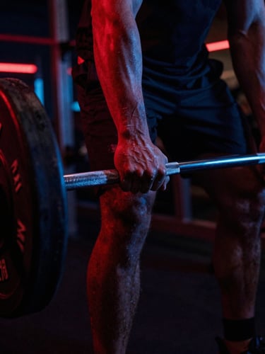 Close-up of chalked hands gripping a heavy barbell in a dark moody gym, dramatic red and blue neon backlighting, 35mm film