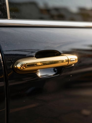 Close-up detail of a polished brass door handle on a pristine black luxury vehicle, sharp focus, rich deep tones, low-sun golden hour lighting