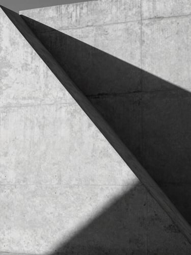 Stark black-and-white architectural geometry, sharp diagonal shadows on a minimalist concrete facade, high-contrast directional light, wide-angle crop.